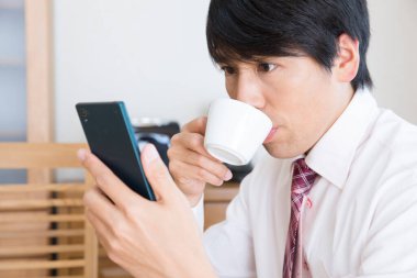 Kahvaltıda akıllı telefon kullanan bir iş adamı. 