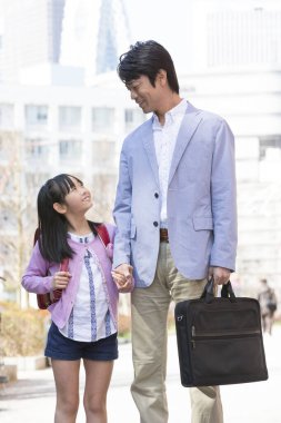 Mutlu Asyalı baba ve kızı şehirde yürüyor. 