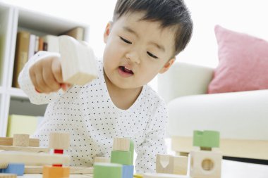 Küçük Asyalı kız ahşap oyuncaklarla oynuyor.