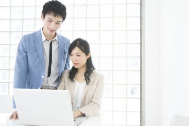 Genç Japon iş adamları ofiste dizüstü bilgisayarla çalışıyorlar.