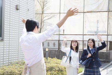 Asyalı bir adam karısına ve kızına veda ediyor.