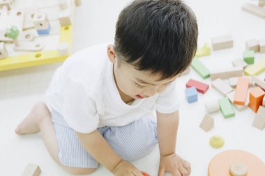 Küçük Asyalı çocuk evde oyuncaklarla oynuyor.