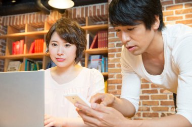 Ofiste bilgisayarla çalışan Asyalı genç kadın ve erkek.