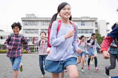 Okul bahçesinde koşan sırt çantalı bir grup Japon çocuk. 