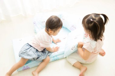 İki küçük çocuk yumuşak yatakta oynuyorlar.