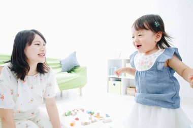 Evdeki oturma odasında annesiyle oynayan tatlı Asyalı küçük kız.