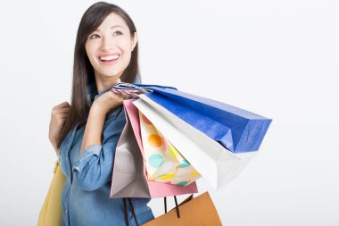 Alışveriş torbalarıyla gülümseyen güzel Japon kadın beyaz arka planda izole bir şekilde yukarı bakıyor. 