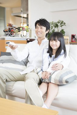 Genç Asyalı baba ve kızı televizyon izliyor. 