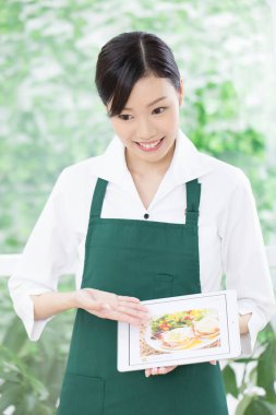 Asyalı garson restorandaki tablette menüyü gösteriyor