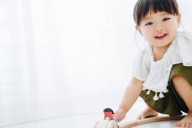 Küçük tatlı Japon kız oturma odasında oyuncaklarla oynuyor.