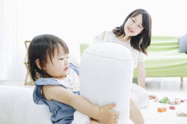 Evdeki oturma odasında annesiyle oynayan tatlı Asyalı küçük kız.