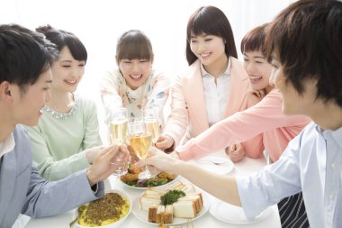 Bir grup Asyalı arkadaş restoranda kadeh kaldırıyor.