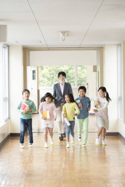 Öğretmenli bir grup Japon çocuk okul koridorunda yürüyor. 