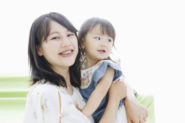 Evdeki oturma odasında annesiyle oynayan tatlı Asyalı küçük kız.