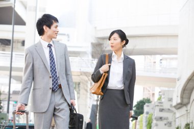 Şehir caddesinde bavulla yürüyen iş adamları.