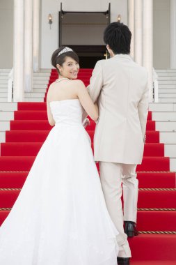 Merdivenlerde kırmızı halıyla yürüyen genç ve güzel bir çiftin arka manzarası. 