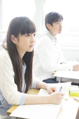 Genç Asyalı öğrenciler sınıfta okuyor.