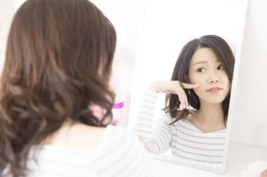 Banyoda aynaya bakan genç bir kadın.