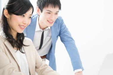 Genç Japon iş adamları ofiste dizüstü bilgisayarla çalışıyorlar.