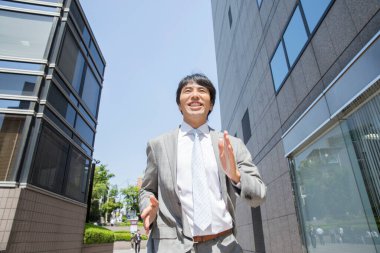 Genç Asyalı işadamı şehirde yürüyor. 