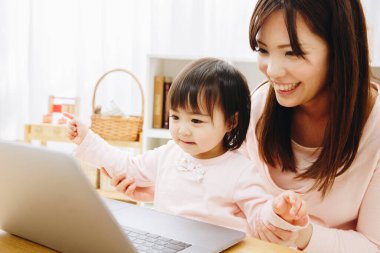 Evde dizüstü bilgisayarı olan küçük bir anne ve kız.