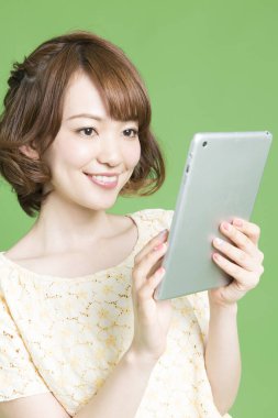 Yeşil arka planda tablet bilgisayar kullanan güzel Japon kadının portresi 