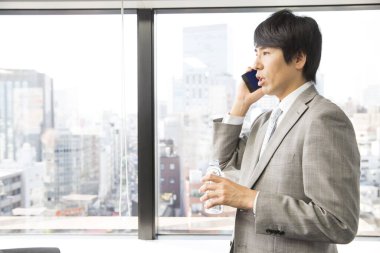 İş adamı cep telefonu ve içme suyu ile konuşuyor. 