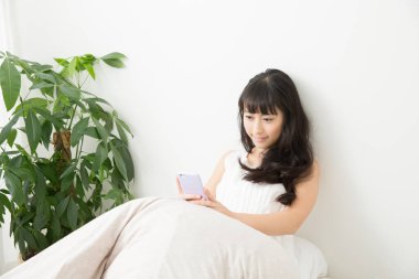 Yatakta cep telefonu kullanan kadın. 