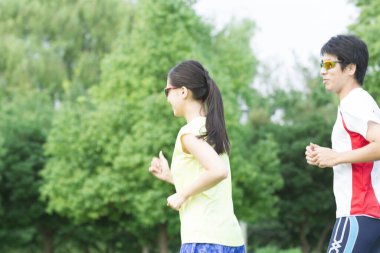 Sportif genç Asyalı çift parkta koşuyor.