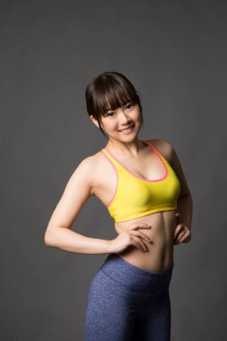 Gri arka planda spor kıyafetler giyen kadın. 