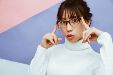 Güzel Asyalı kadın beyaz süveter giyiyor ve gözlük takıyor. 