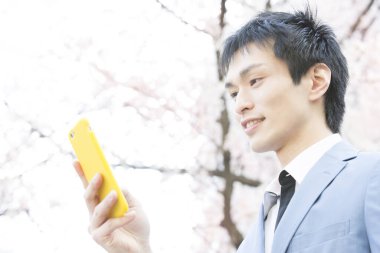 Genç adam parkta cep telefonu kullanıyor. 