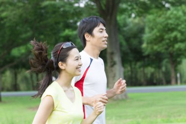 Sportif genç Asyalı çift parkta koşuyor.