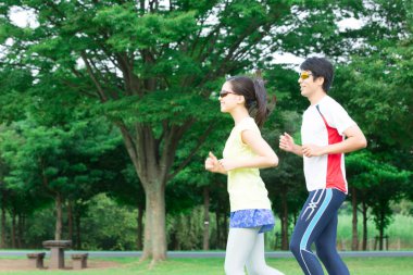 Sportif genç Asyalı çift parkta koşuyor.