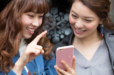 İki arkadaş sokakta akıllı telefon kullanıyor.