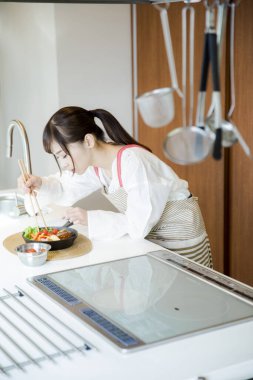 Güzel Asyalı kadın mutfakta yemek yapıyor.