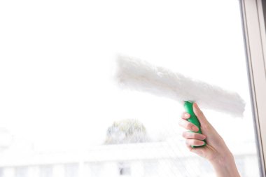 Kadın elleri pencereyi temizliyor. 