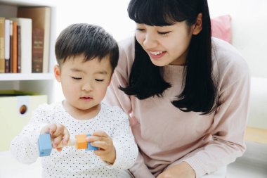 Evde annesiyle oynayan tatlı Japon çocuk.