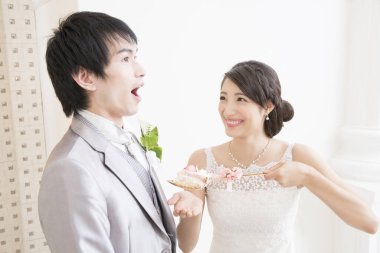 Güzel, mutlu, genç gelin yakışıklı damadı düğün pastasıyla besliyor.        