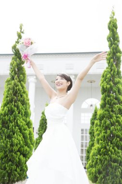 Güzel mutlu genç gelinin portresi. Kollarını kaldırıp düğün buketini tutuyor.