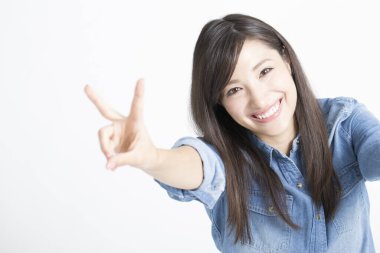 Güzel genç Asyalı kadın zafer jesti sergiliyor, stüdyo çekimi. 