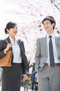 Şehir caddesinde kiraz çiçekleri olan iki Japon iş adamı.