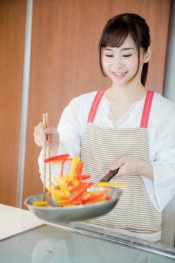 Genç Japon kadının portresi mutfakta yemek hazırlıyor. 