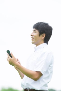 Genç Asyalı adam cep telefonu kullanıyor.