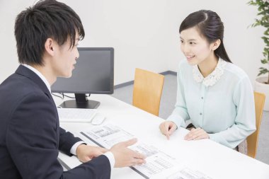 Genç Asyalı işadamı kadın müşteriyle birlikte çalışıyor.