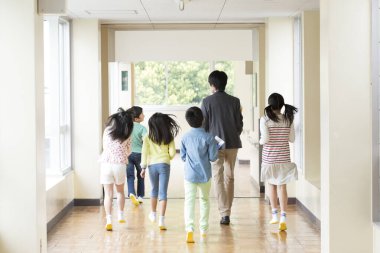 Okul koridorunda yürüyen çocuklar ve öğretmenler