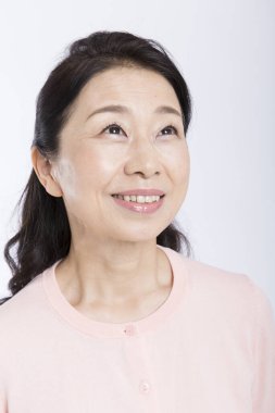 Yan tarafa bakan Asyalı son sınıf öğrencisi kadın beyaz arka planda izole edilmiş. 