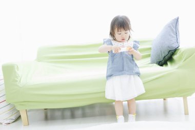 Evdeki oturma odasında oynayan tatlı Asyalı küçük kız.