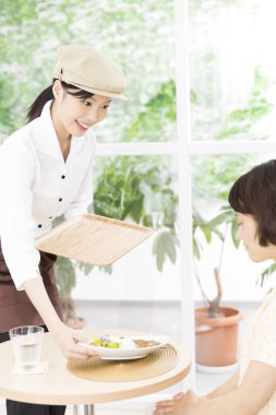 Ziyaretçilere yemek servisi yapan Asyalı garson. 