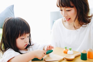 Evdeki oturma odasında annesiyle oynayan tatlı Asyalı küçük kız.